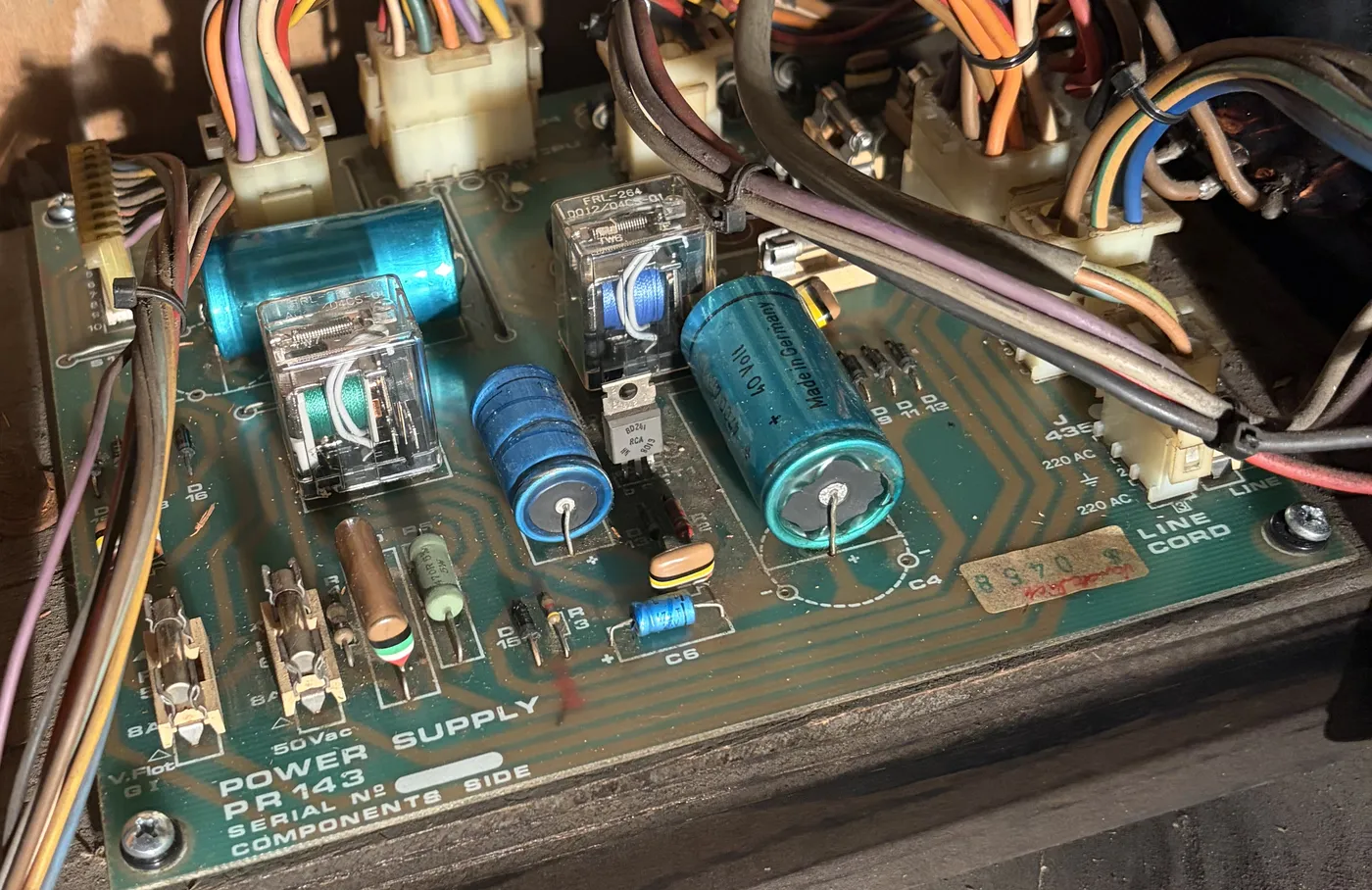 The PR143 power supply board in the bottom of the cabinet, with relays, large blue filter capacitors and fuse holders