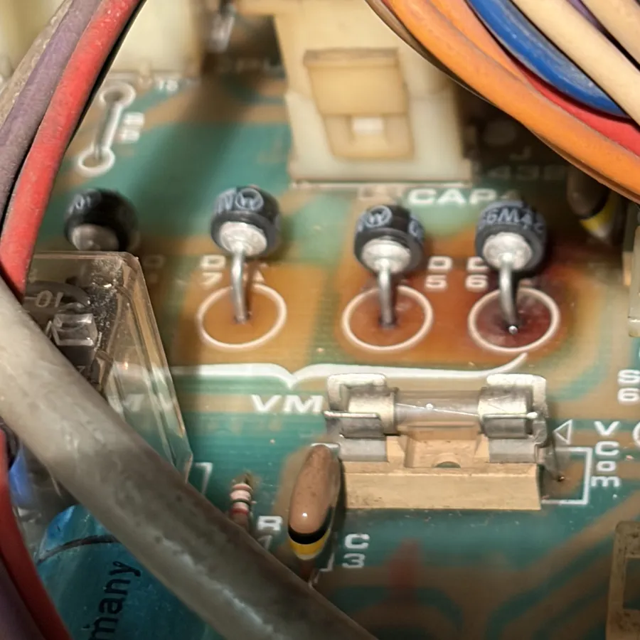Closeup of four black round diodes forming the full bridge rectifier, with a glass fuse in its holder below them